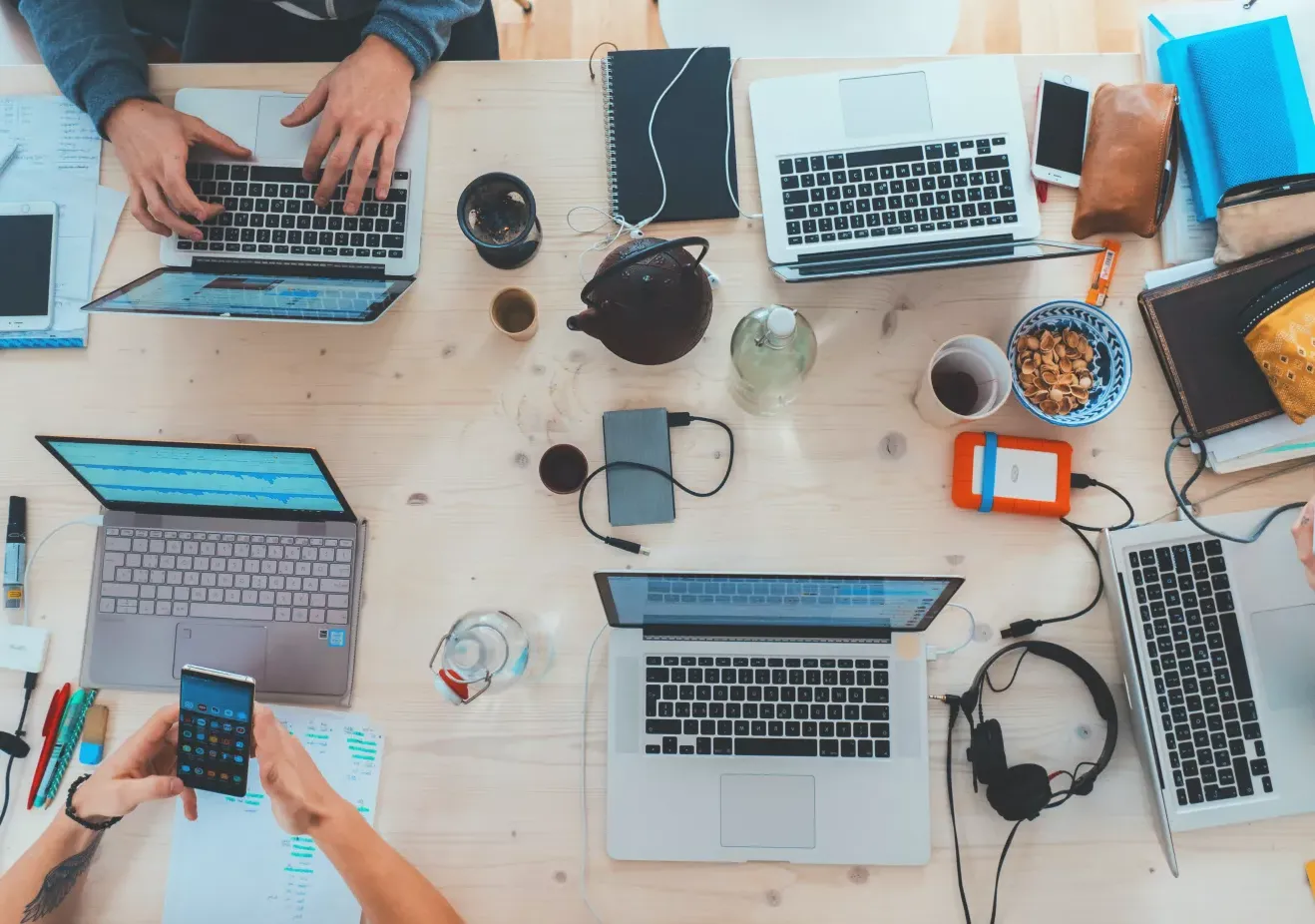 People sitting around a table top with different electronic, hearing and writing tools on it. 