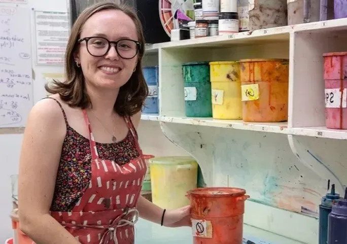 Francis Miller posing in front of paints at the Fabric Workshop and Museum in Philadelphia